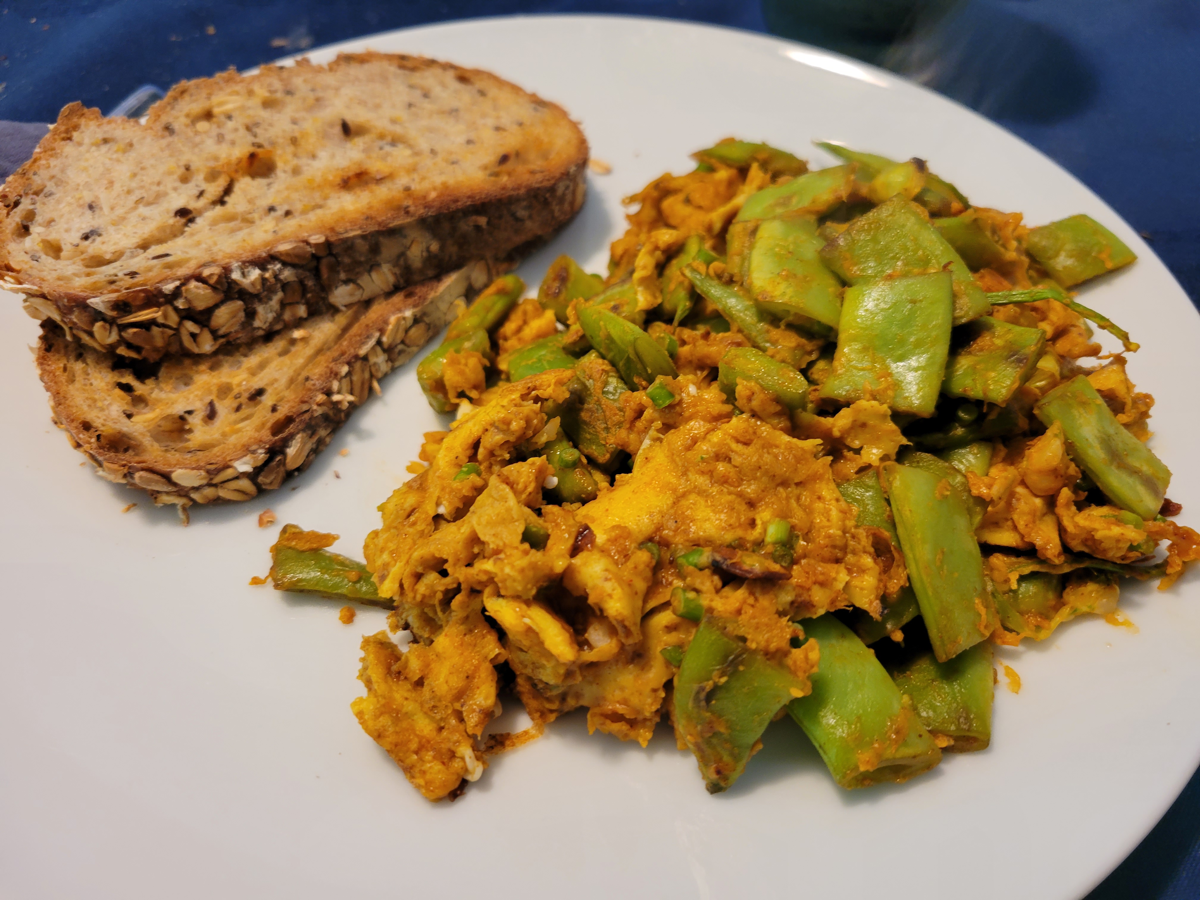 plate of scrambled eggs with romano beans, accompanied by toast