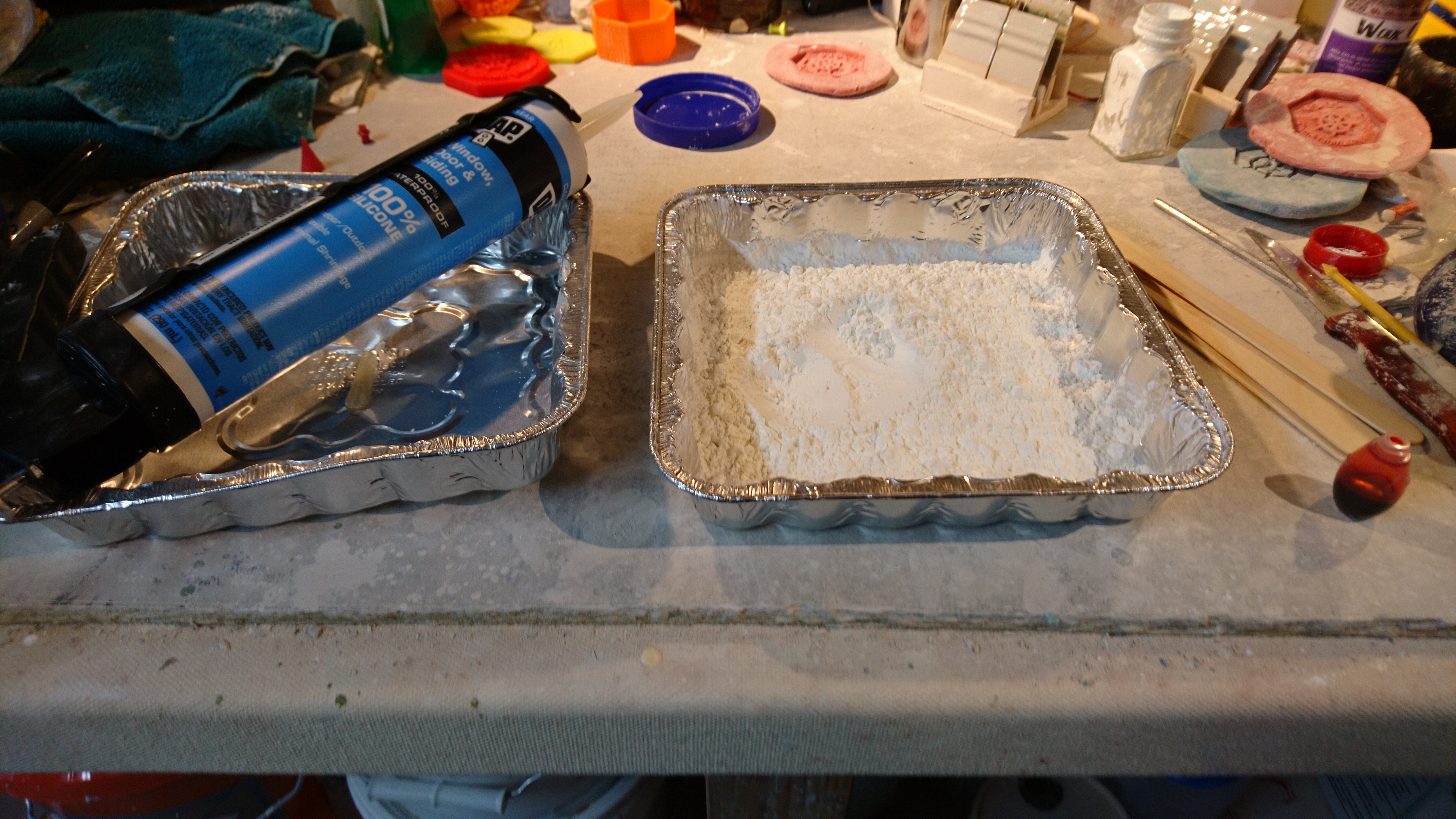 picture of two foil trays, a tube of silicone, and a lot of cornstarch