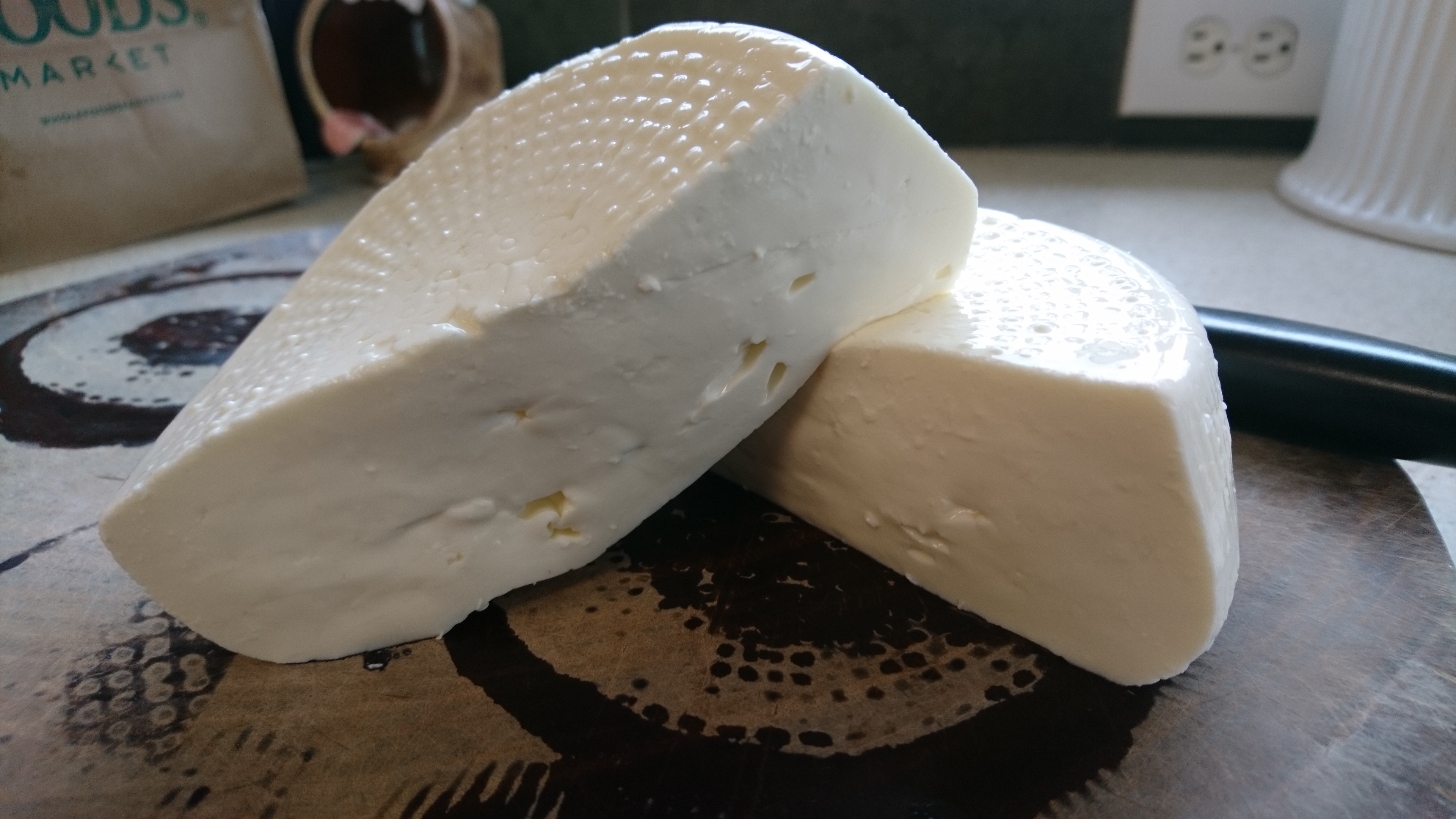 crescenza cheese wheel cut in half on a plate