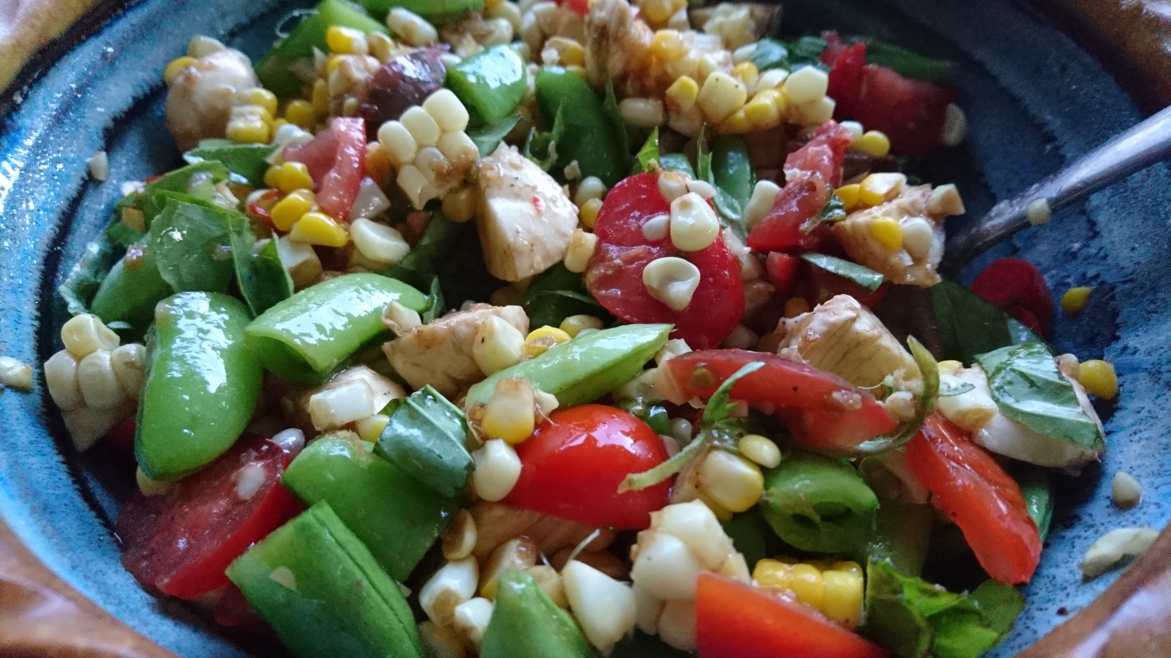 snap pea, tomato, and corn salad in a ceramic bowl
