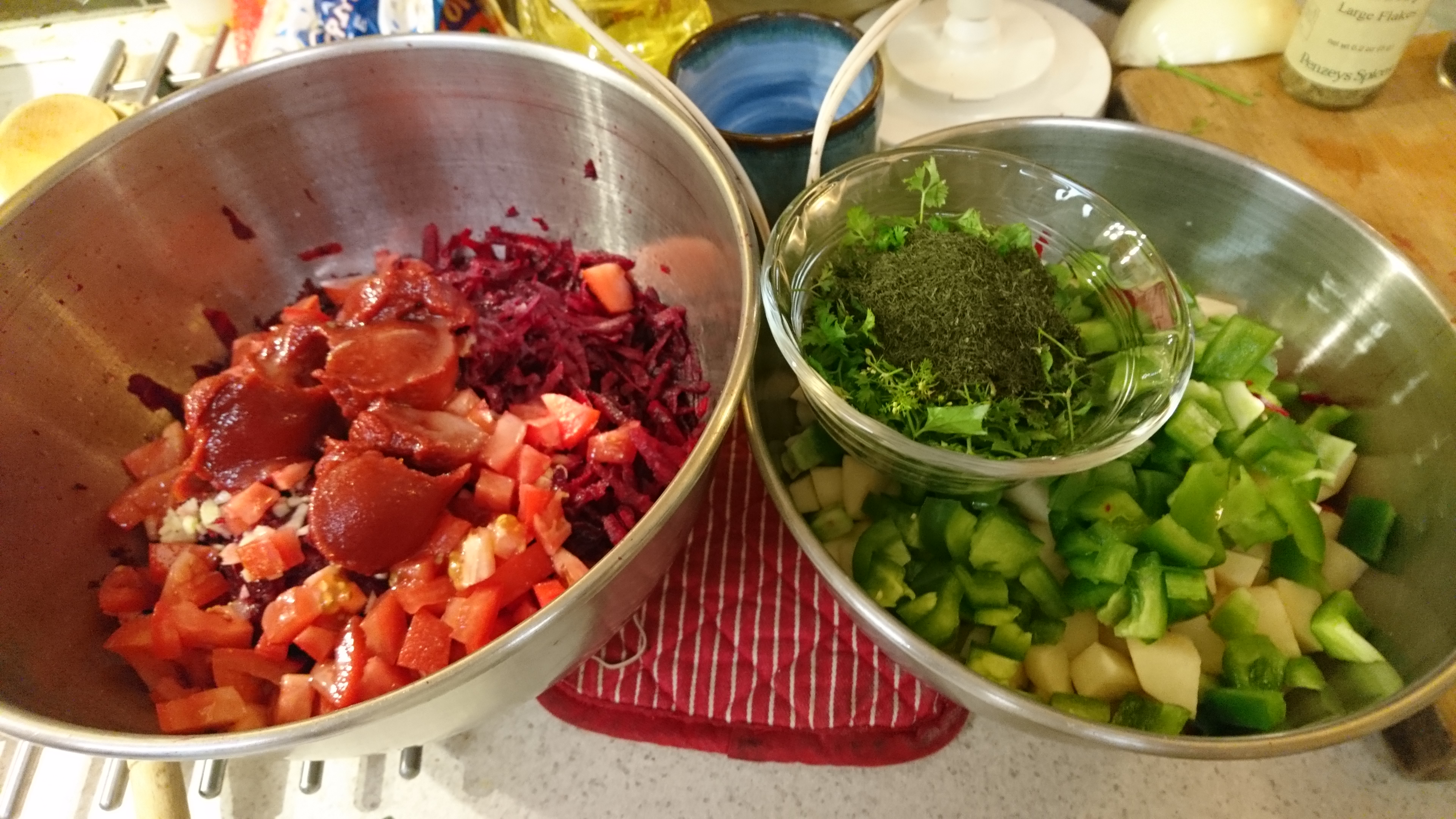 prep bowls for borscht; left one contains beets and other red ingredients, right one has green peppers and potatoes