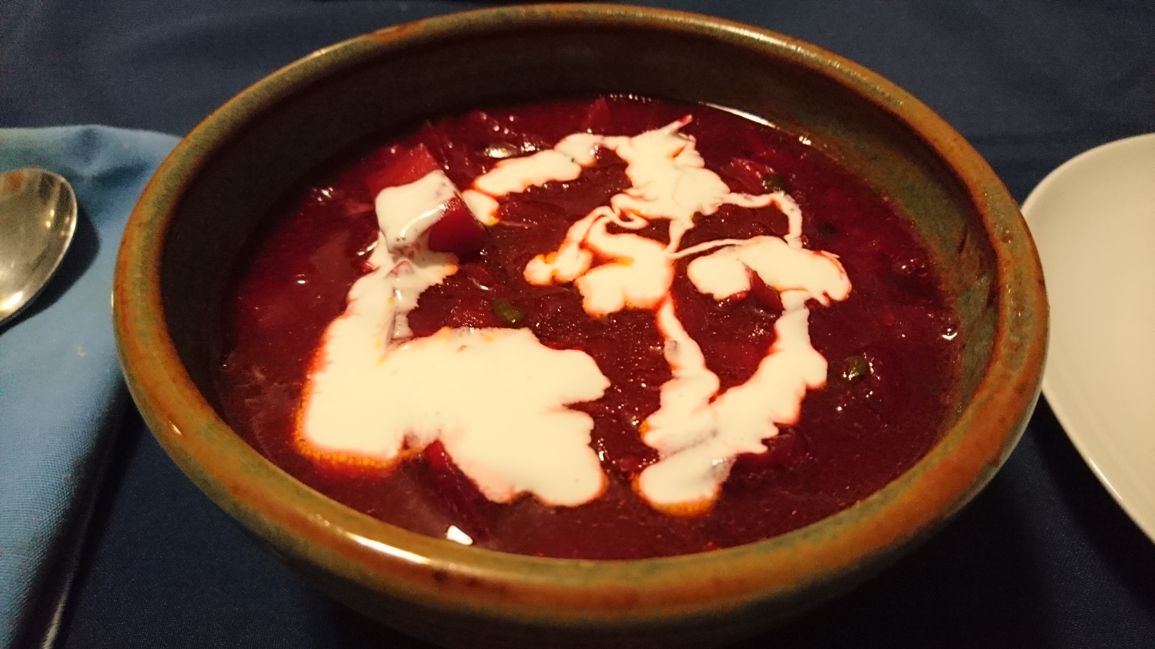 bowl of hot borscht with sour cream drizzled on top