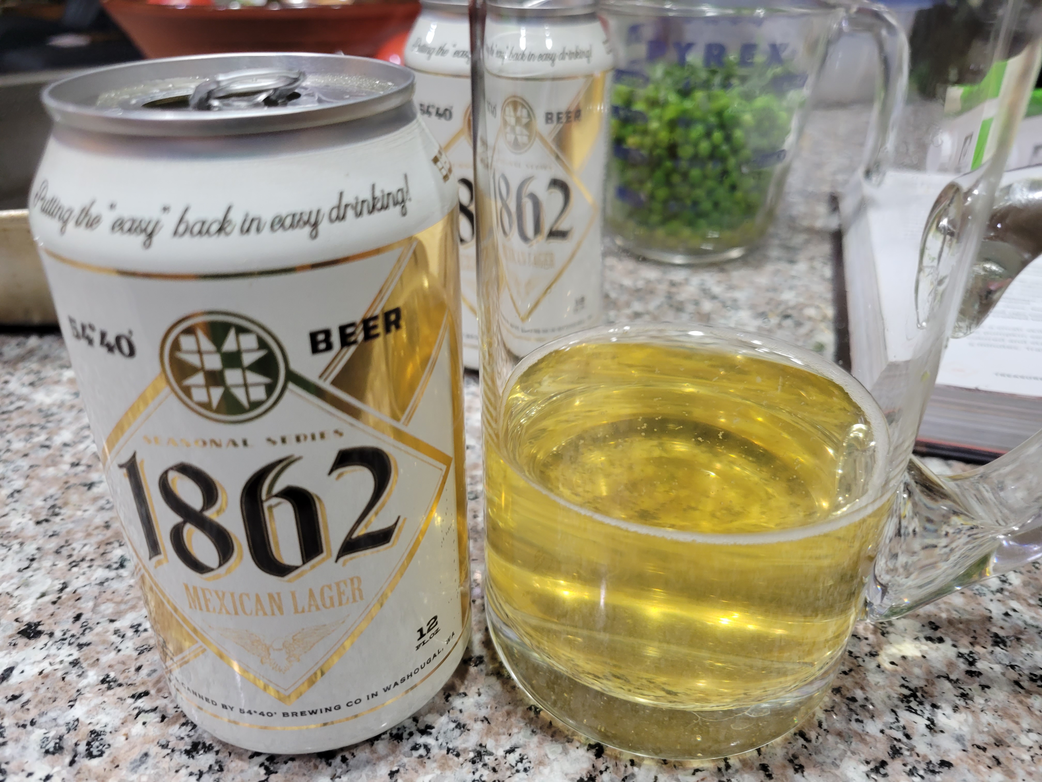 a glass beer mug with a light clear lager next to a can of the 1862