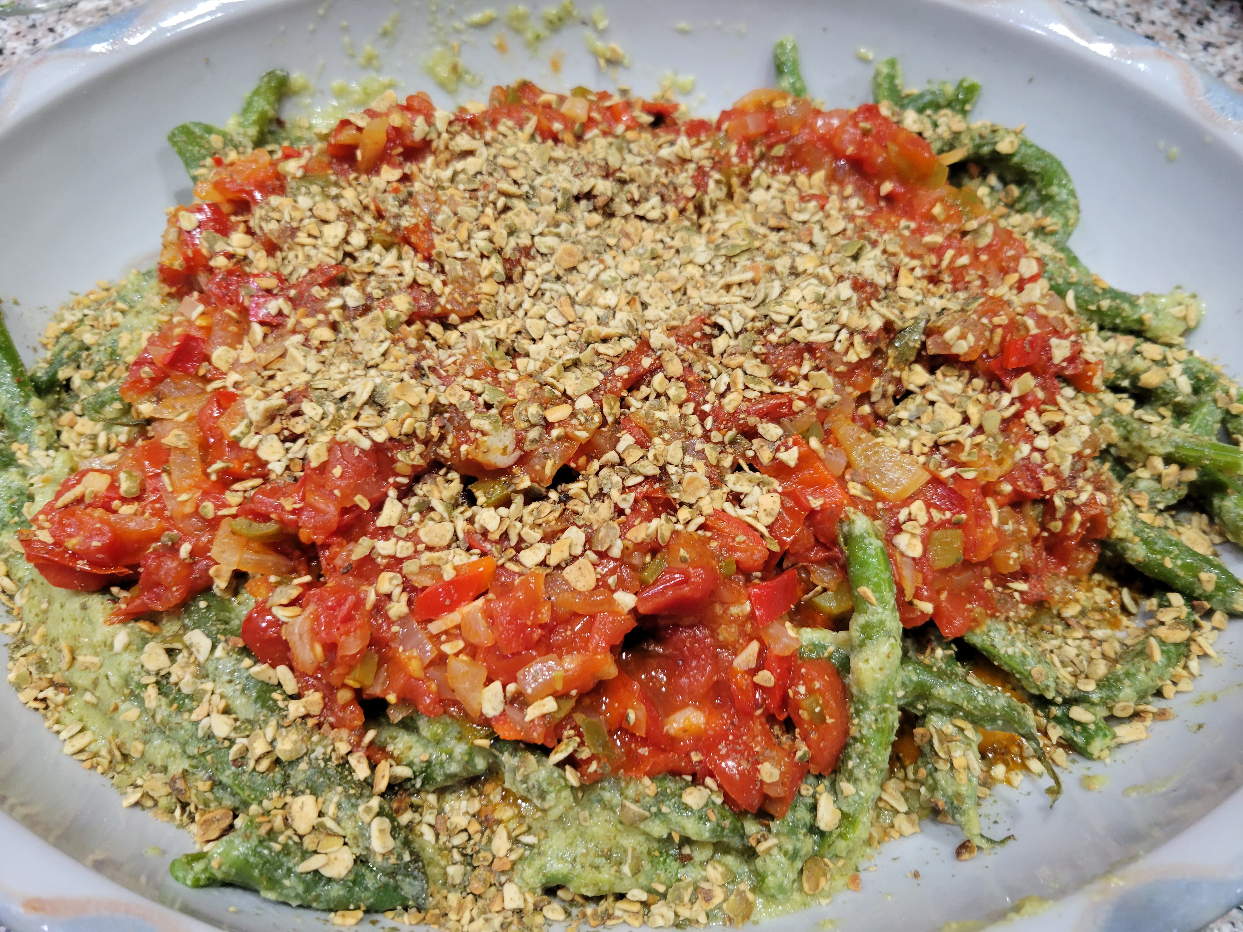 platter of green beans in corn sauce.  They're topped with a homemade tomato salsa and sprinkled with ground pumpkin seeds