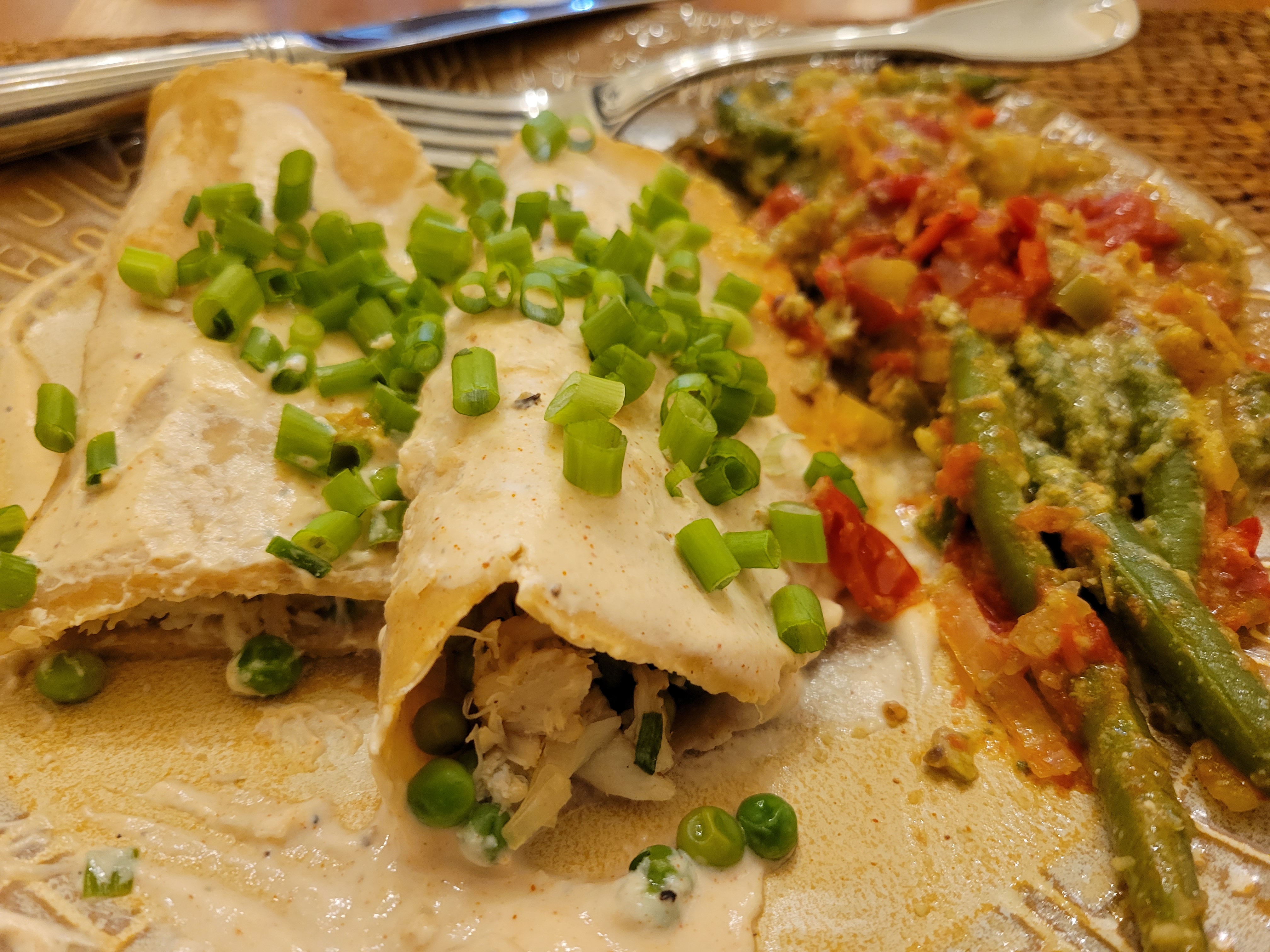 plate of thanksgiving food, including two enchiladas in a cream sauce with green onions and green beans with tomato salsa