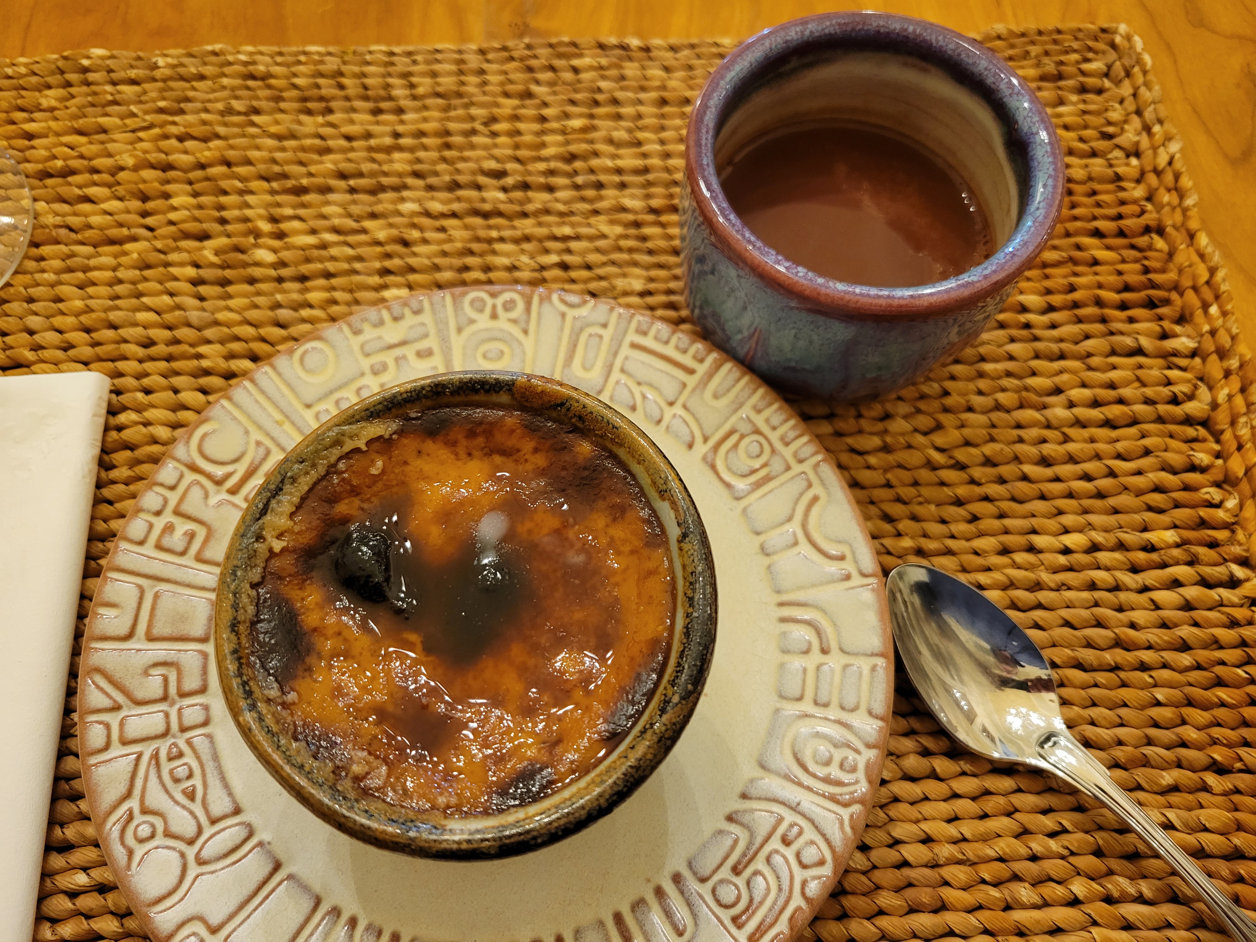 a small ramekin of cajeta custard, next to a ceramic teacup with hot chocolate