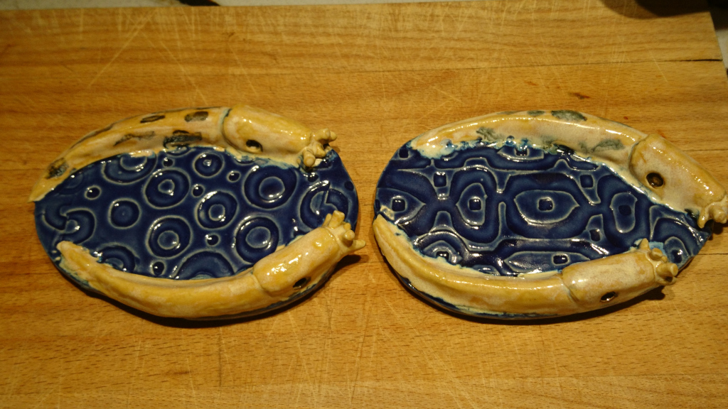 two old navy-blue suggy soap dishes, oval