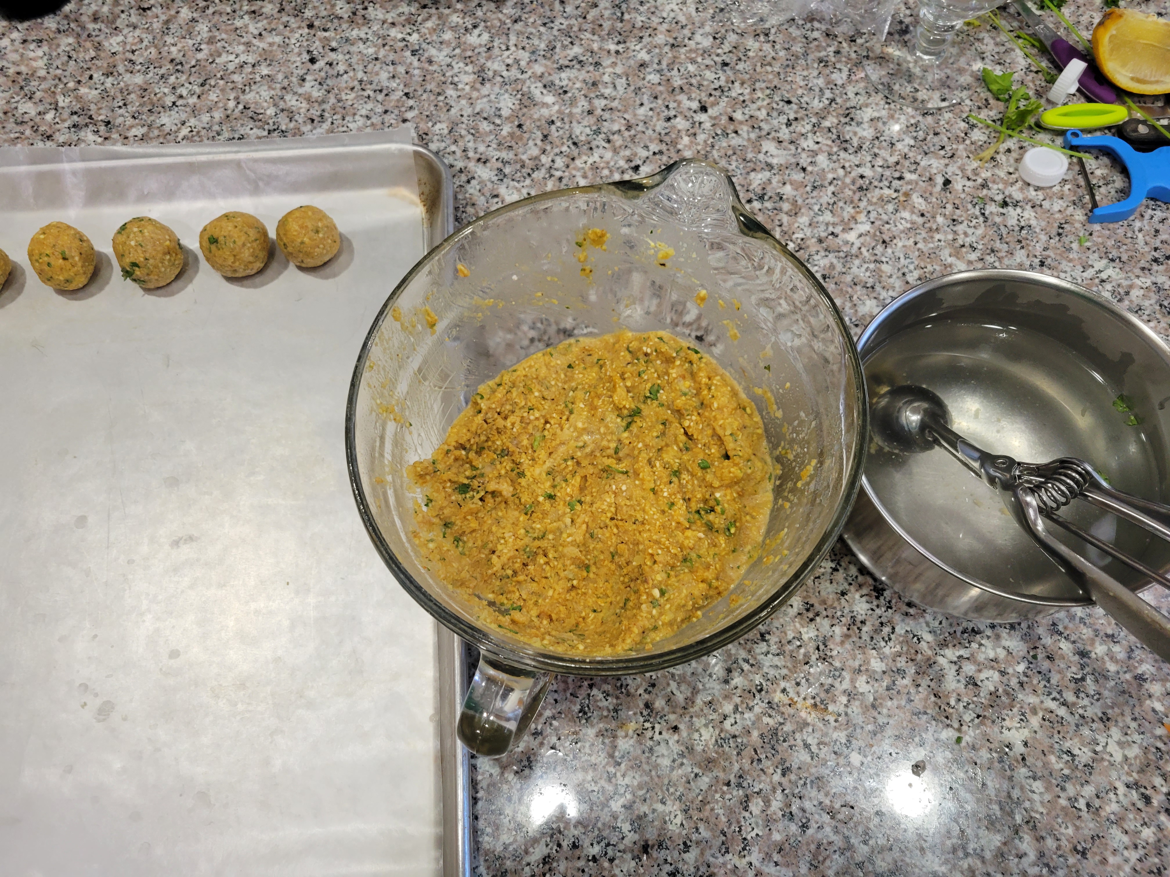 starting to scoop matzoh balls, with cookie scoop and several on a lined tray