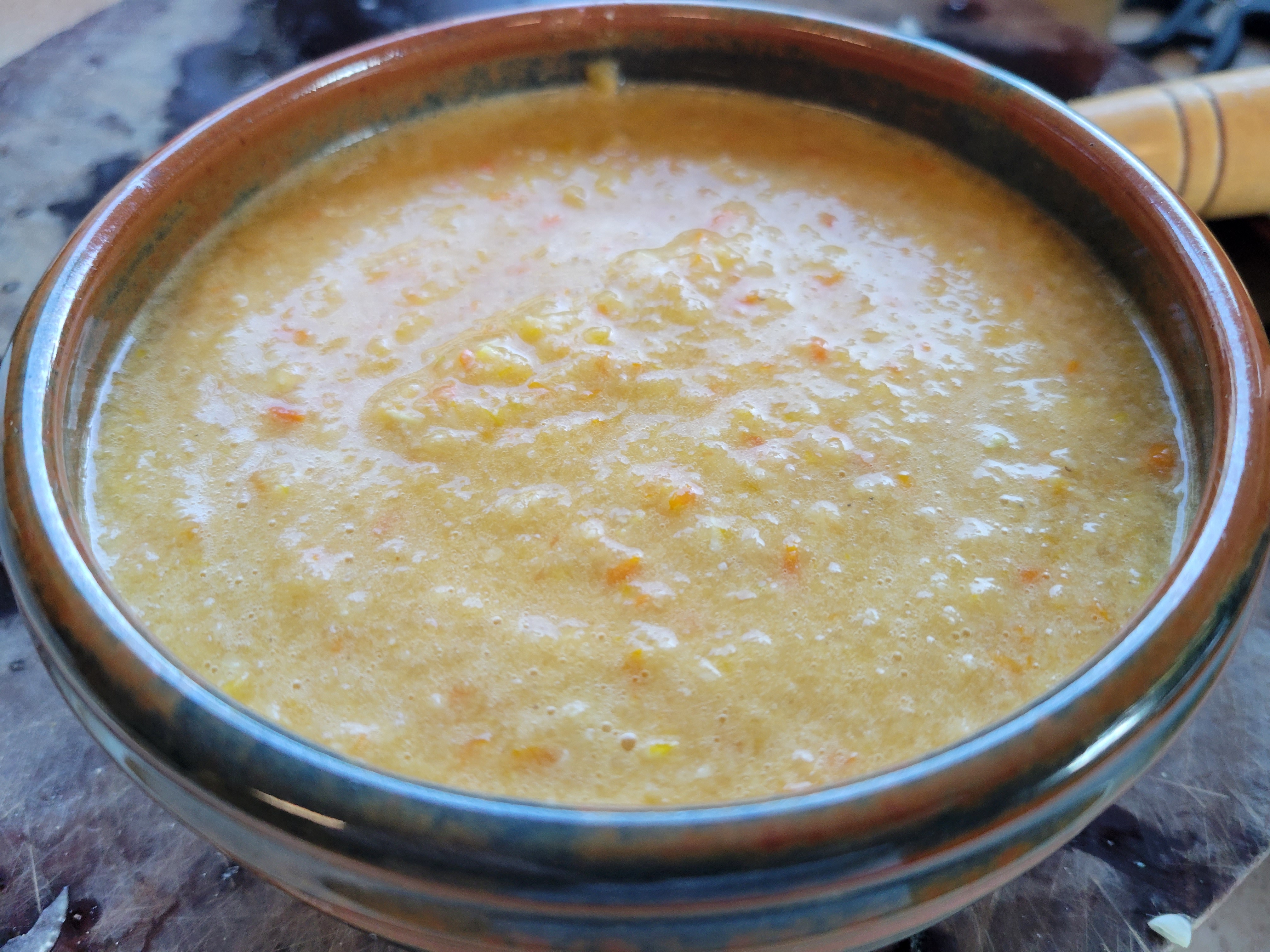 handmade blue ceramic bowl full of yellow-orange gazpacho