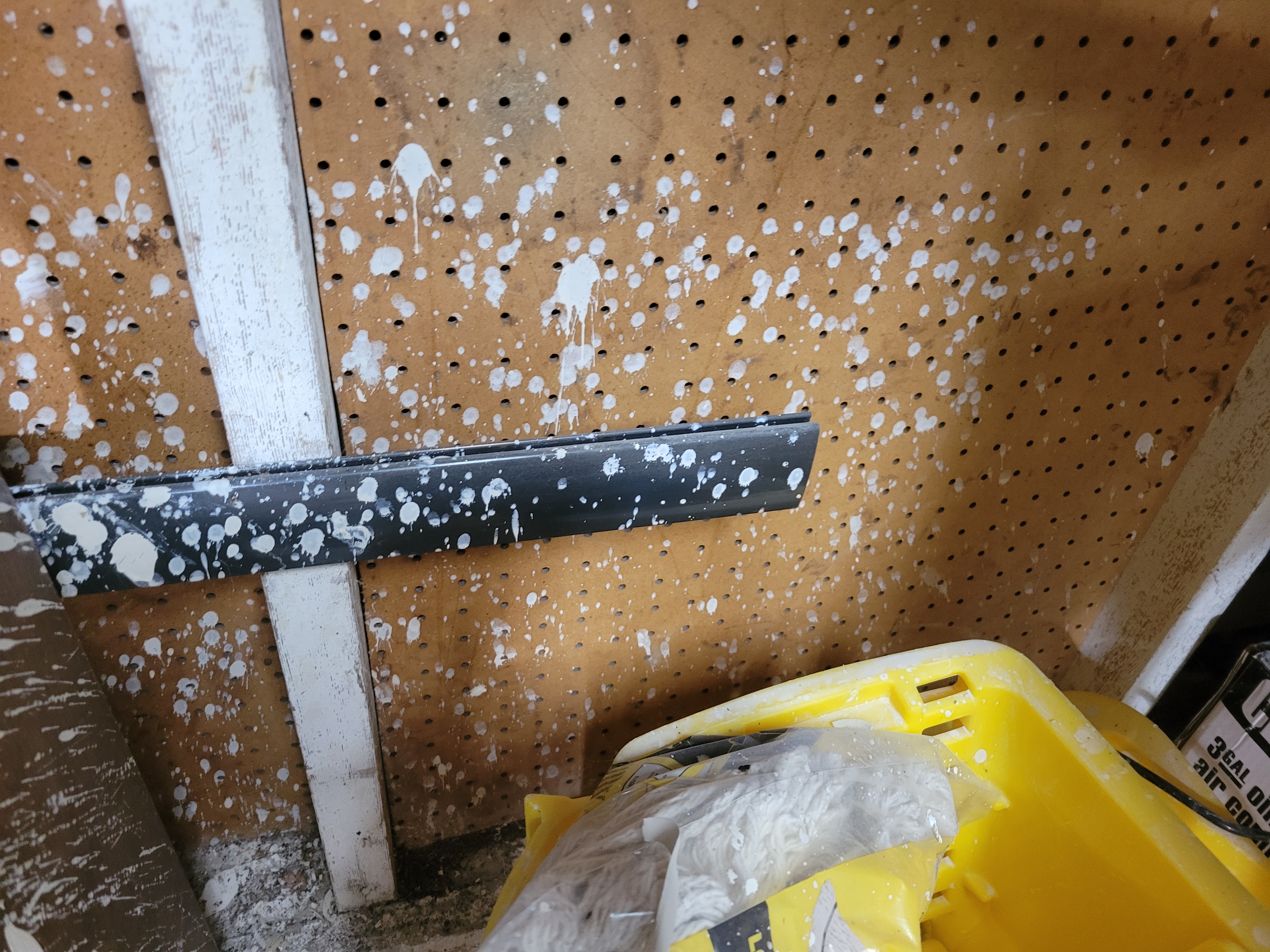 pegboard wall of the studio, polka-dotted with splashes of white clay slip