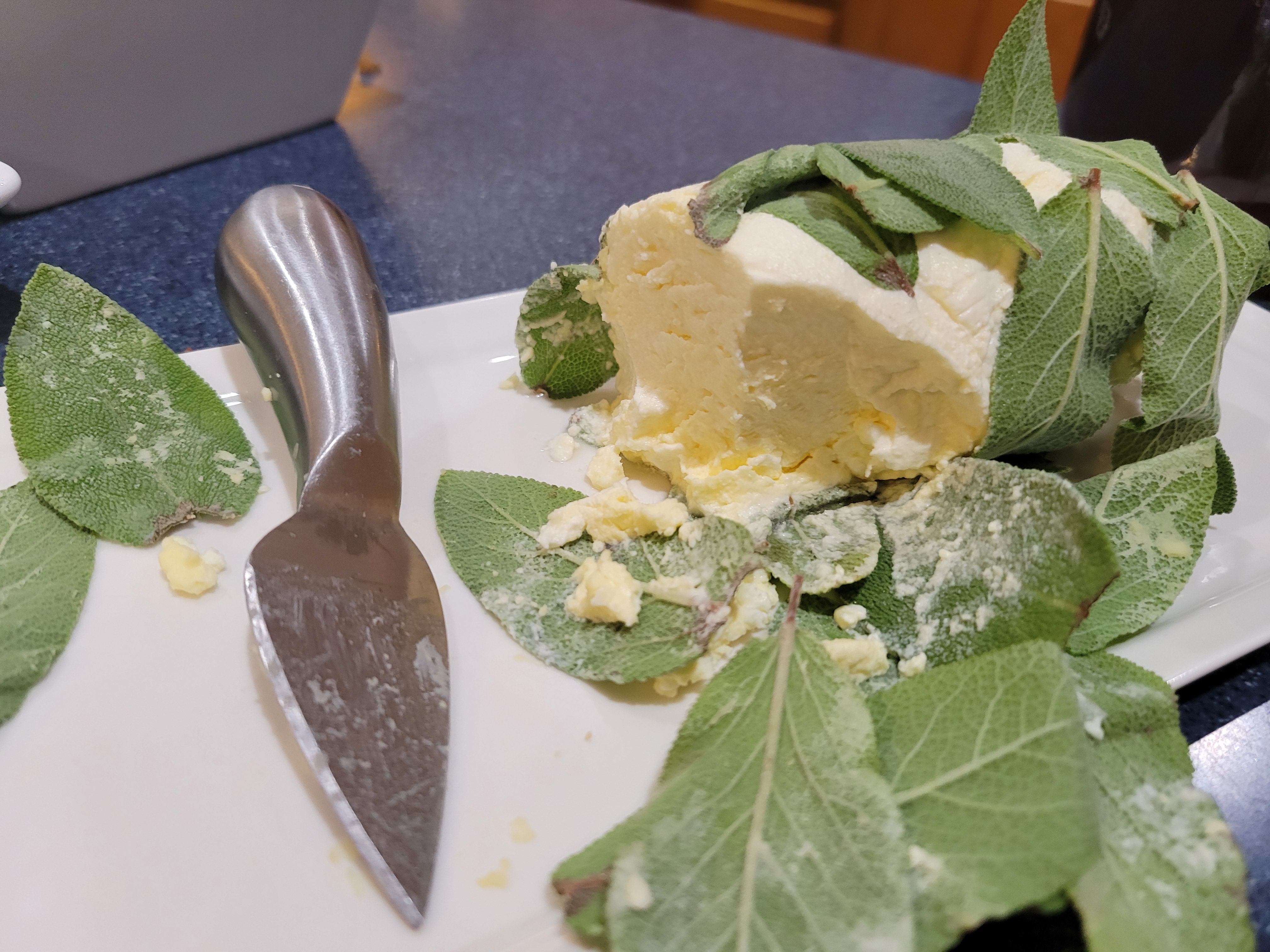 roll of Neufchâtel cheese wrapped in sage leaves on a plate