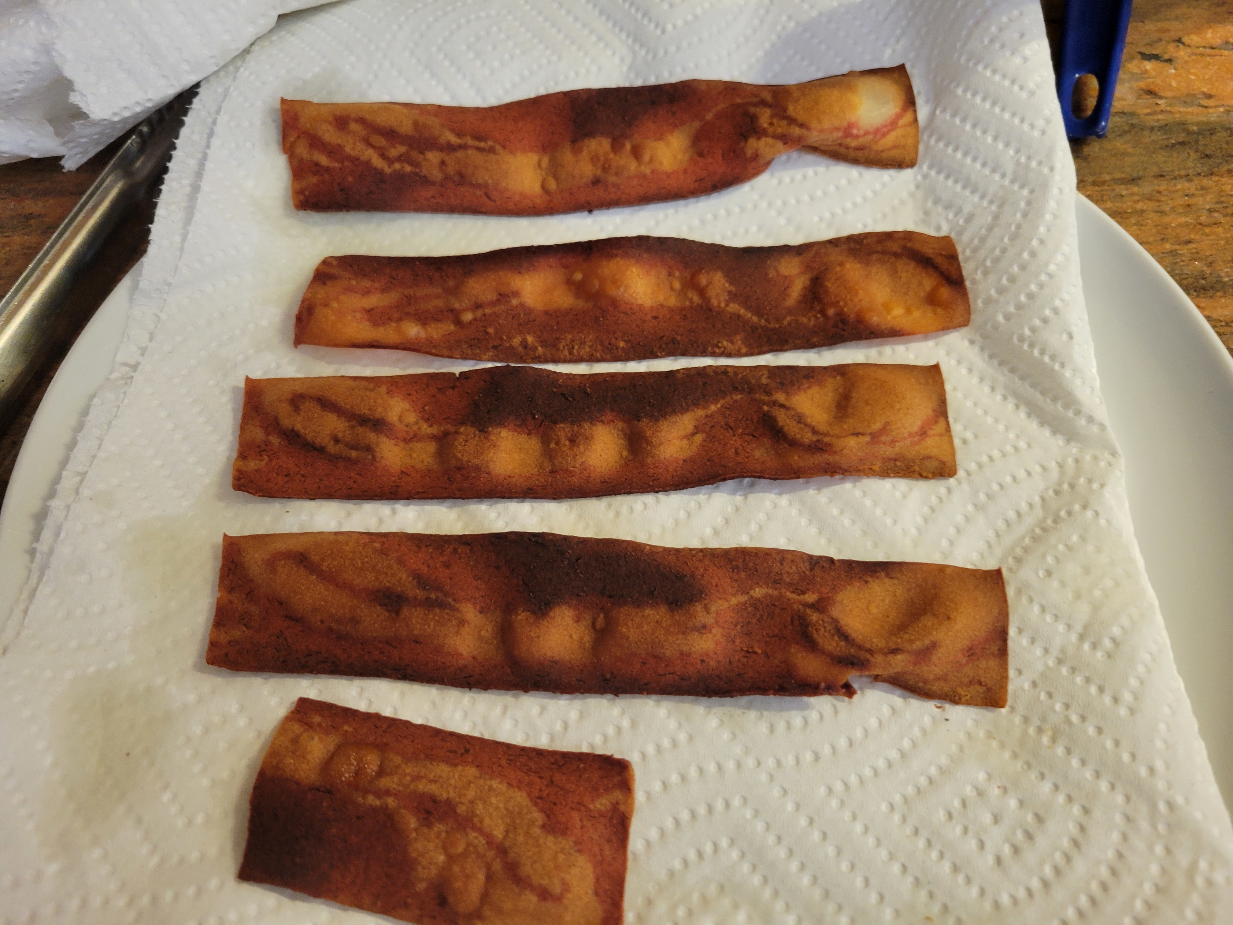 four and a half strips of fake bacon cooling on a paper towel