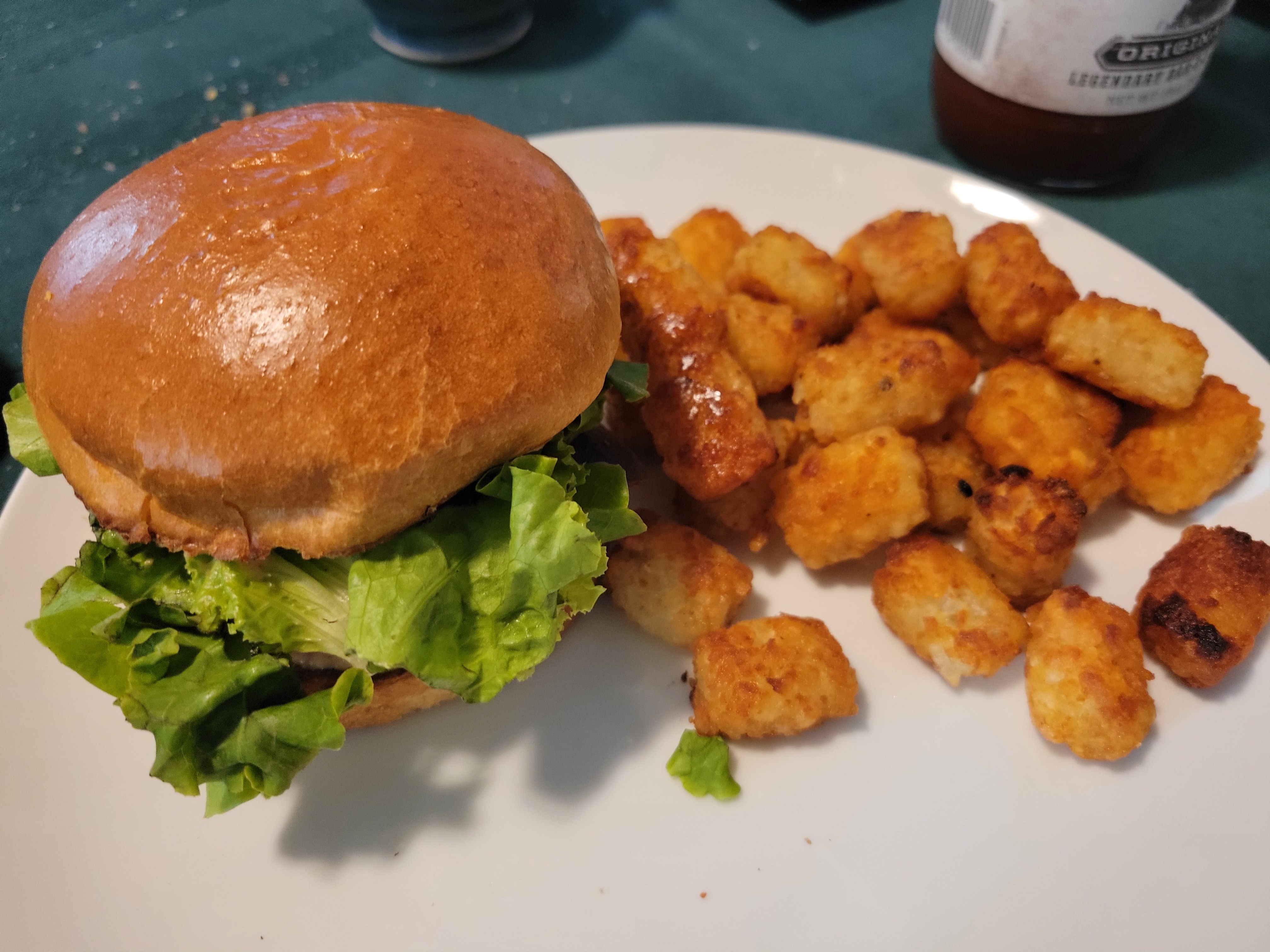 photo of an FLT sandwich on a plate, next to a small pile of tater tots